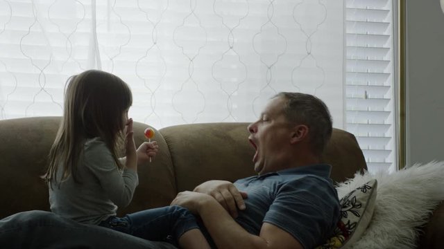 Medium shot of father and daughter playing with lollipop / Provo, Utah, United States