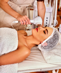 Ultrasonic facial treatment on ultrasound face machine. Woman receiving electric lift massage at spa salon. Electronic stimulation female muscles microcurrent therapy . Technologies of rejuvenation.