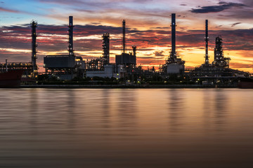 Obraz premium Oil refinery or petrochemical industry with ship at Sunset with water reflection in thailand. for Logistic Import Export background, Petroleum, petrochemical plant.