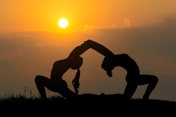 Silhouette young women practicing yoga at sunset