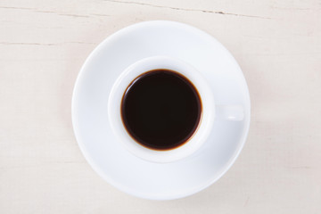 Top view of empty white cup coffee with black coffee put on white wood table with space for copy.