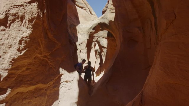 Wide shot of couple hiking in narrow slot canyon / Escalante, Utah, United States
