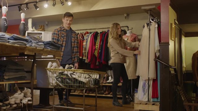 Medium shot of man watching woman shopping for vintage dress / Provo, Utah, United States