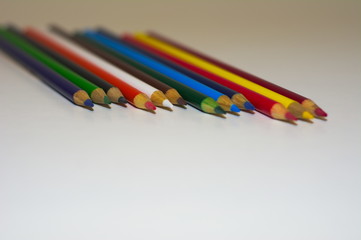 Different colored pencils stacked next to each other portraying diversity and strength shot from a side angle on a white background