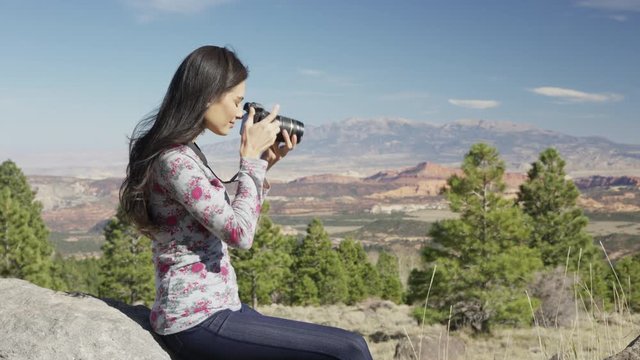 Medium zoom in shot of woman photographing in desert / Boulder, Utah, United States