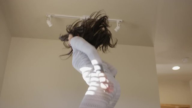 Medium low angle shot of woman jumping and dancing on bed / Escalante, Utah, United States