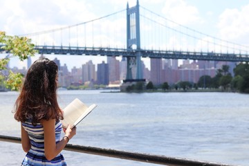Young attractive woman reading a book by waterfront 
