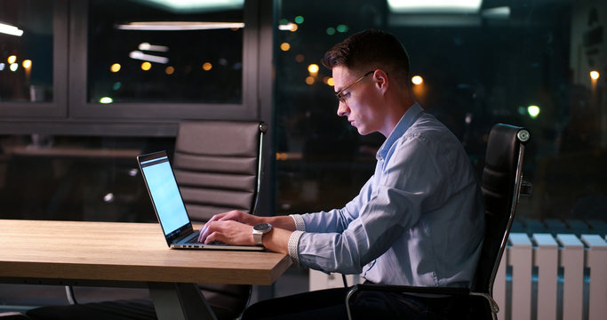 man working on laptop in dark office