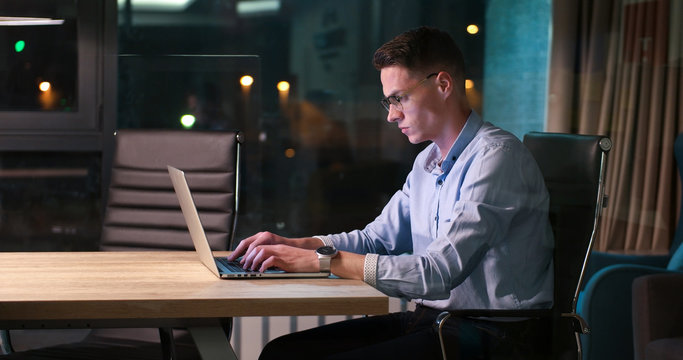 man working on laptop in dark office