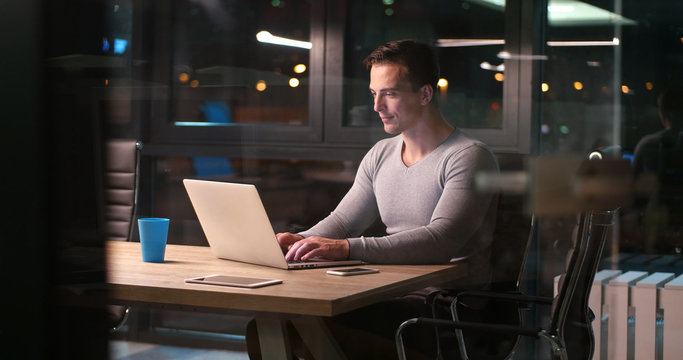 man working on laptop in dark office