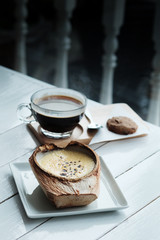 The Coconut Creme Brulee is sugary flavours and drink with hot americano black coffee on white wooden table background 
