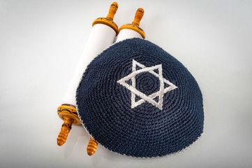 Judaism and jewish religious holiday concept with a closed Torah and a kippah also called a yamaka....