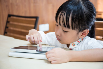 Naklejka premium Asian Chinese little girl playing tablet computer