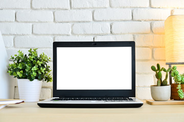 Laptop computer on wood desk with white brick wall background