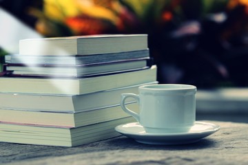 Open book and pile of books on table closeup outdoor green nature blur background