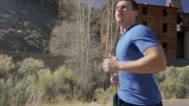 Medium slow motion tracking shot of man running in neighborhood / Antimony, Utah, United States