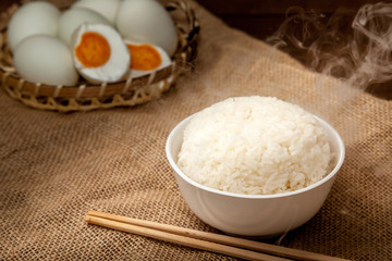 Eating rice with salted eggs by using chopsticks on wooden background