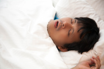 Asian man is snoring in bed and his have sleep apnea, Health care concept.