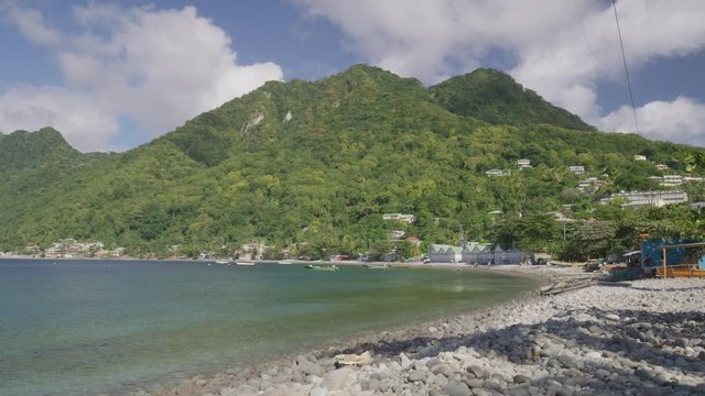 Wide panning shot of distant waterfront houses / Scotts Head, Dominica
