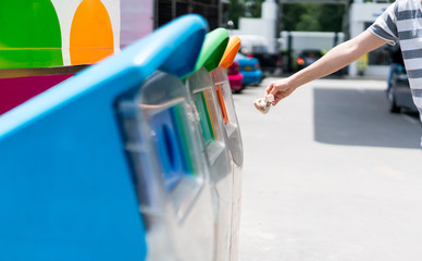 Woman hand putting used paper in recycled bin at parking area