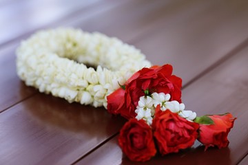 Thai style of jasmine garland with fabric pattern closeup on wooden table background. Thai traditional of mother's day