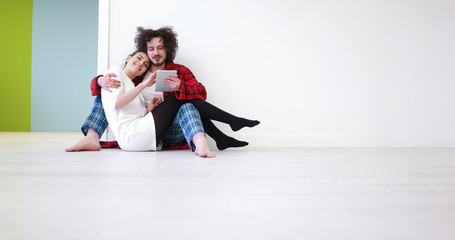 Young Couple using digital tablet on the floor