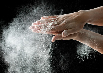 Fototapeta na wymiar White flour on hands on a black background