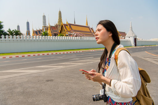 Woman on smart phone walking on grand palace