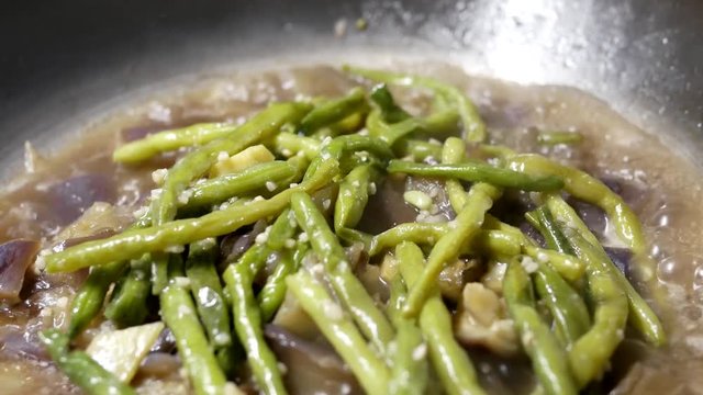 Close up of a woman cooking eggplant and garlic green bean hot pot in frying pan