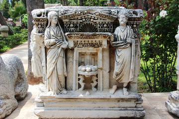 Fototapeta premium Ancient stone Lycian sarcophagus with the sculptures of men and women in antique costumes - toga. in a Park on the street next to Antalya archaeological Museum. Turkey