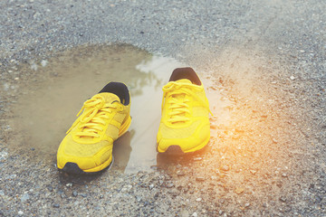 Yellow shoes on puddle after raining.