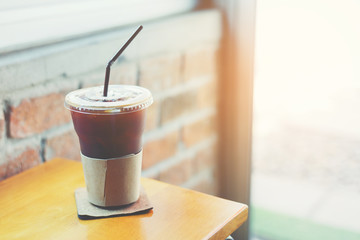 Iced black coffee in a plastic glass put on the wooden table for refresh brain and body.