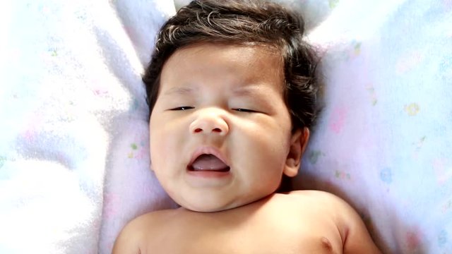 Thai baby sneezing in bed.
