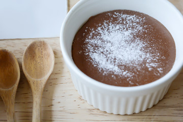 Chocolate lava in white cup with powder and wood spoon on wood table.Dessert on wooden prop.Coffee shop dessert.