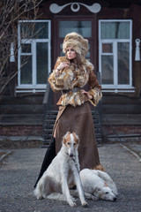 Beautiful girl, model with pet dogs in a beautiful attire in the yard of her house. Fashion, style, beauty, dogs, friendship.