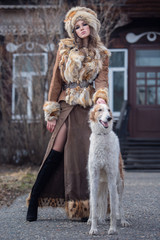 Beautiful girl, model with a pet dog in a beautiful outfit in the courtyard of her house. Fashion, style, beauty, a dog.