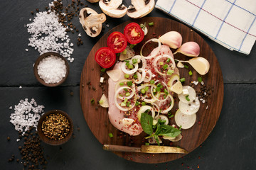 Fillet raw chicken. Fresh chicken meat on wooden board with fresh organic vegetables for cooking. Top view, close-up. Rustic style. Ingredients for dietary healthy eating.