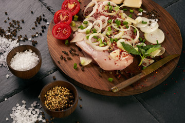 Raw food grocery full of proteins on wooden brown cutting rustic board on black stone background. Chicken fillet, onion, herbs. Healthy sport diet background. Healthcare lifestyle or proteins concept