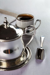 coffee in a beautiful mug with a silver holder and silver sugar bowl