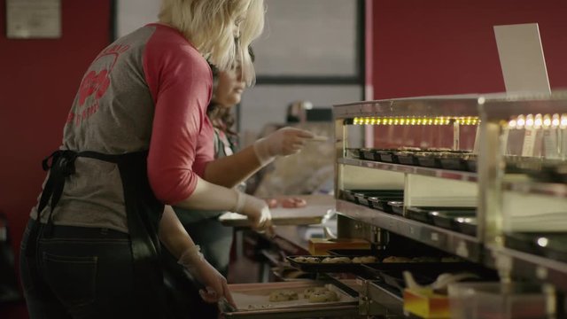 Medium shot of bakers placing cookies in bakery display case / Salt Lake City, Utah, United States