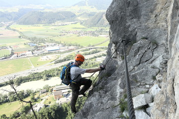 Mann klettert die Felswand rauf