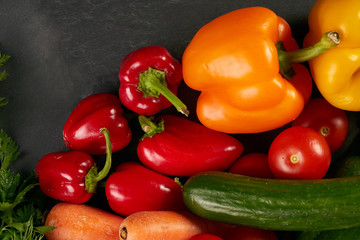 Fresh vegetables with greens on a black stone textured background. Healthy vegetarian eating.