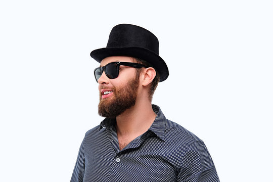 Bearded hipster male in sunglasses and cylinder hat.
