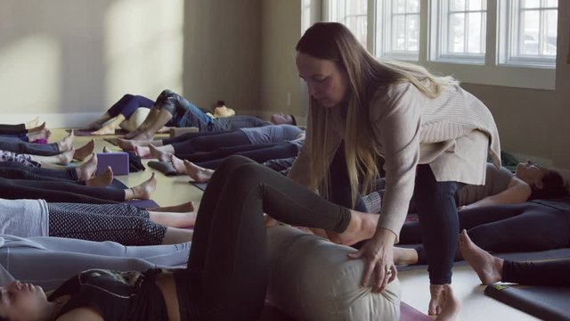 Medium slow motion panning shot of yoga class in corpse pose / Provo, Utah, United States