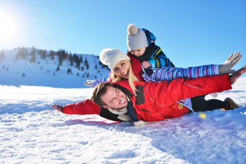 happy young family playing in fresh snow at beautiful sunny winter day outdoor in nature