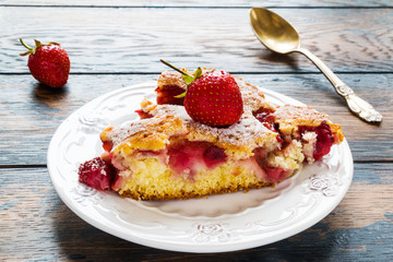 A piece of strawberry cake on a white  vintage plate on the wooden rustic table.