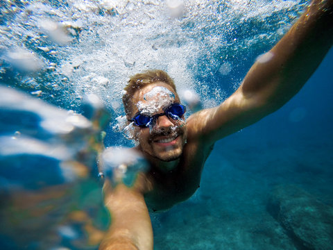 Energy man with smile taking a selfie photo underwater during summer.