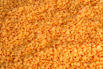 Plastic pellets, orange industrial beads background.