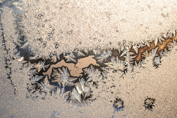 Magical frost painting on the window glass in the cold winter sunrise