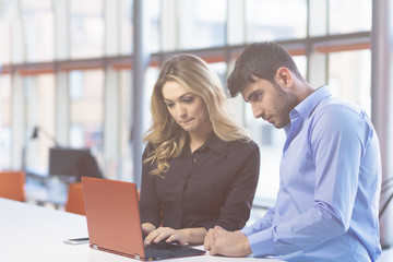 Young couple working together on a laptop in the office. Teamwork concepts.